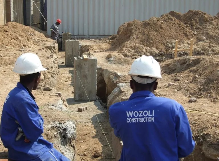 Wozoli site crew in branded worksuits inspecting foundation trench & columns